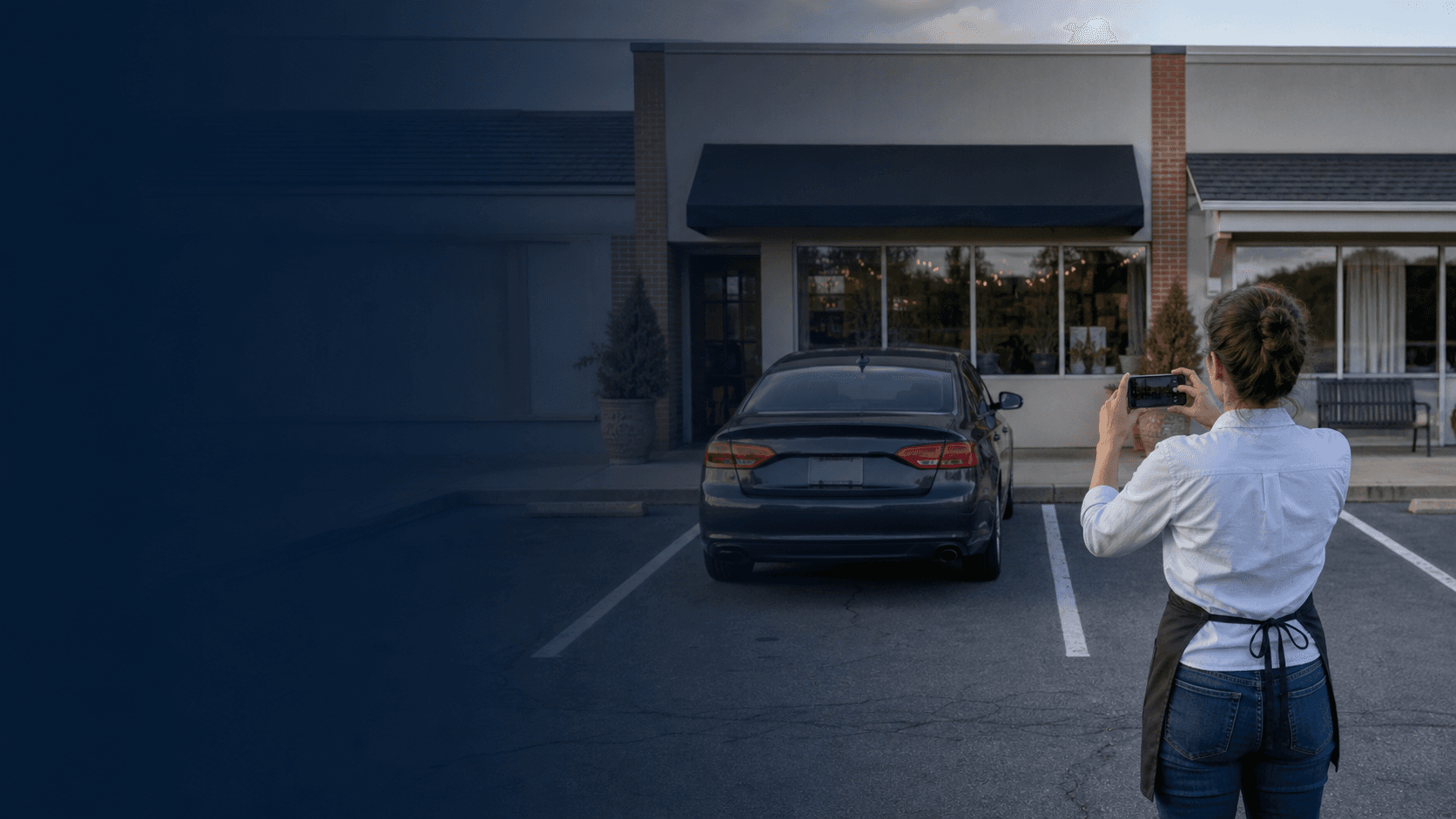 Small-business owner photographing an unauthorized vehicle in front of a neighborhood storefront